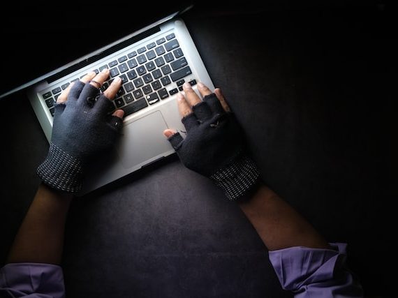 Gloved hands typing on keyboard representing hacking