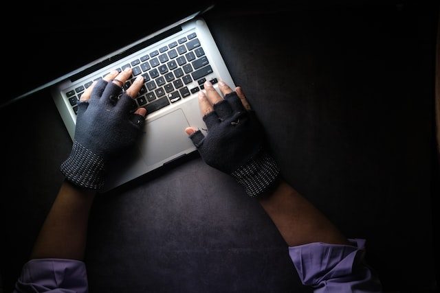 Gloved hands typing on keyboard representing hacking